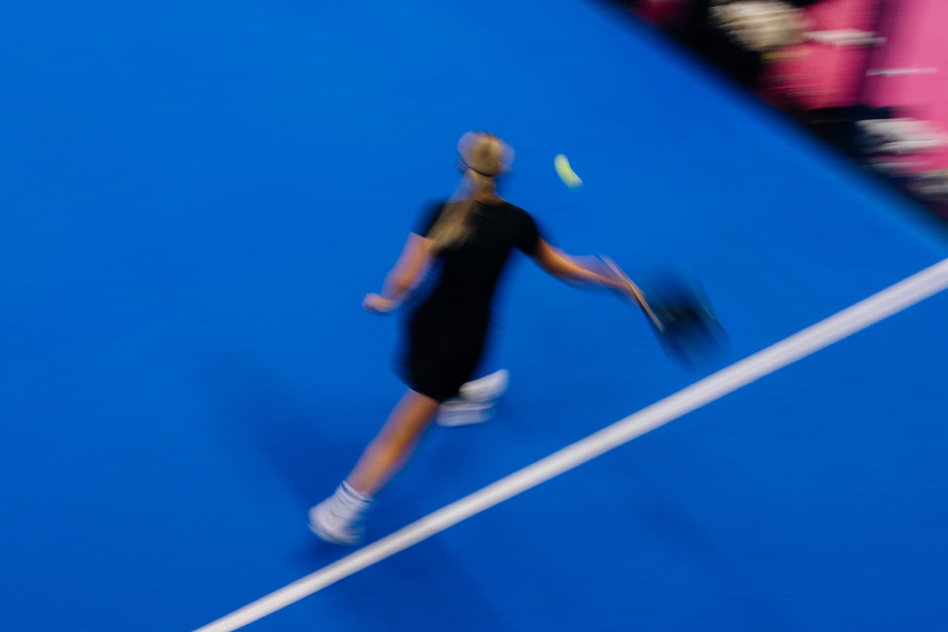 Player reaching low on a blue padel court