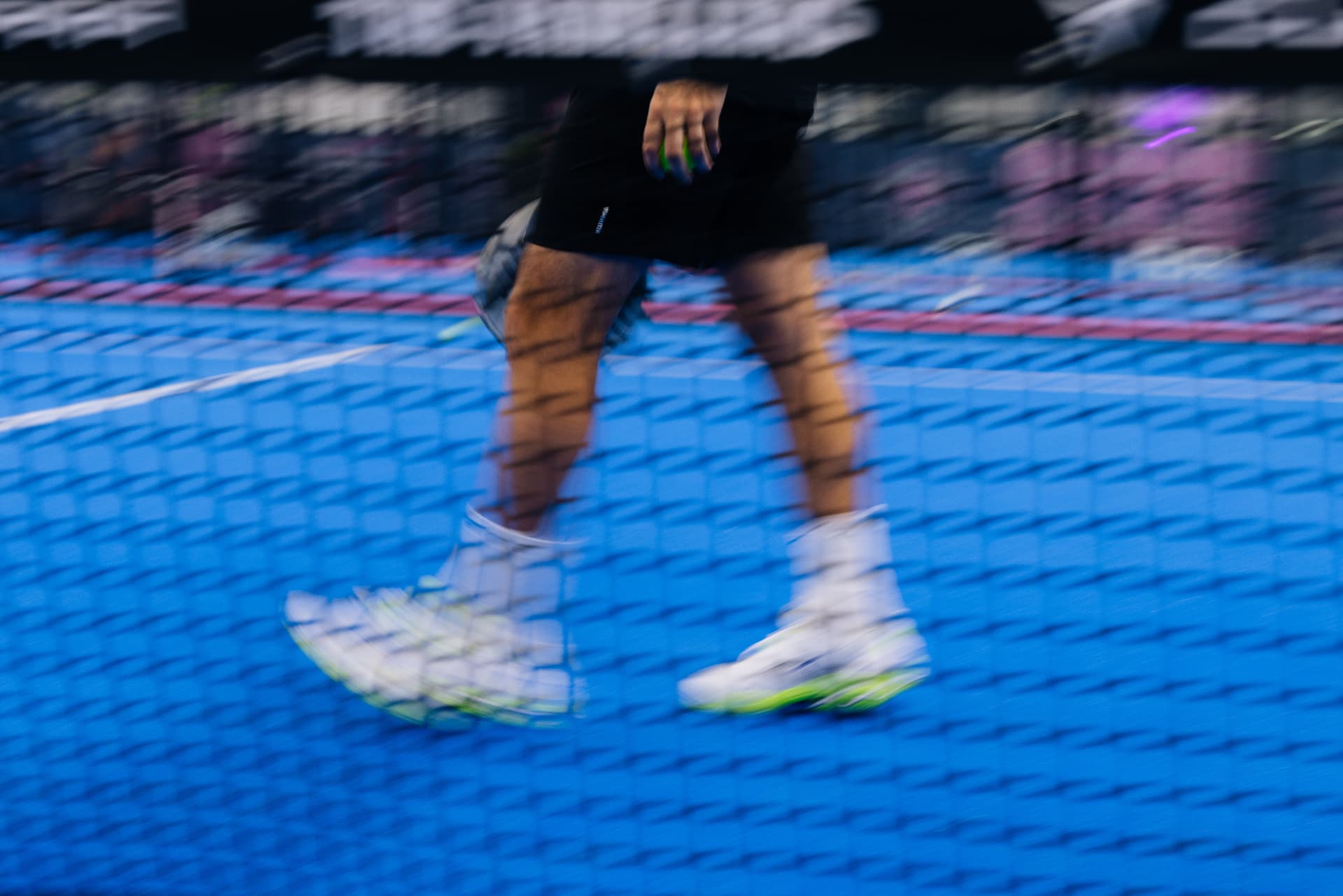Blurred padel action on a blue court
